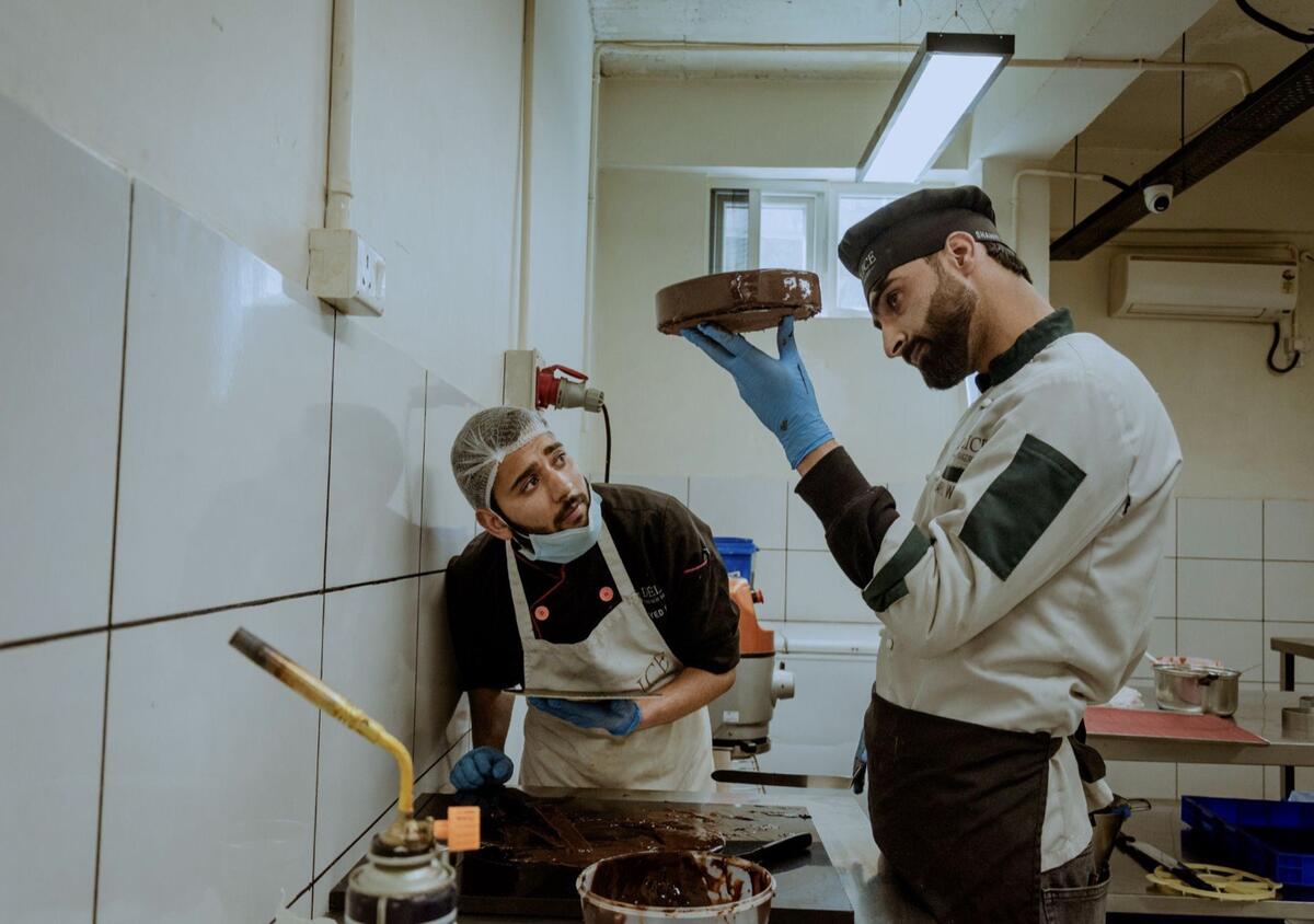 Two bakers checking a chocolate cake